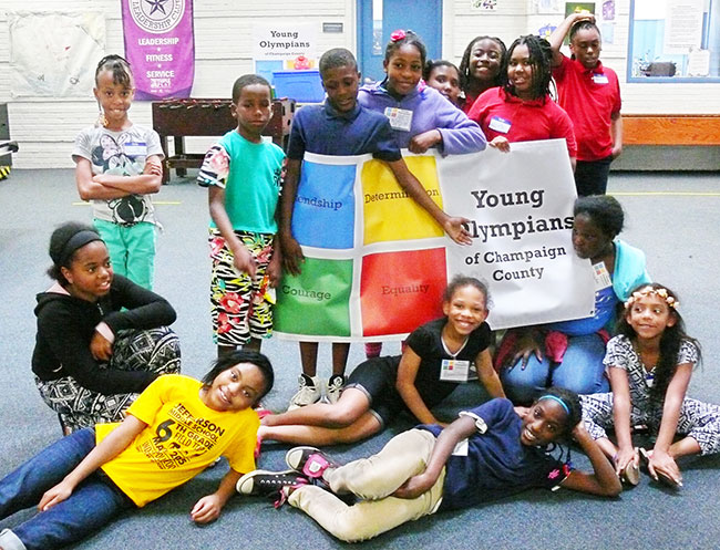 group of 15 grade-school-age kids holding up a banner that reads 'Young Olympians of Champaign County'